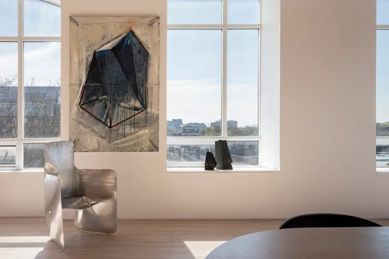 White-walled room with floor-to-ceiling windows overlooking a winter waterfront and bare trees