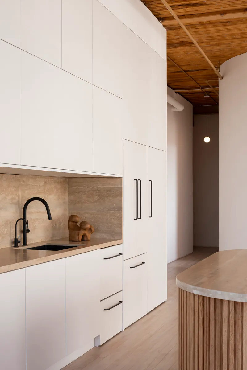 Galley kitchen with white cabinets, travertine backsplash and timber coffered ceiling above