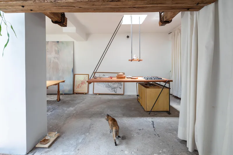 Studio interior with polished concrete floor and timber worktable as a dog walks through