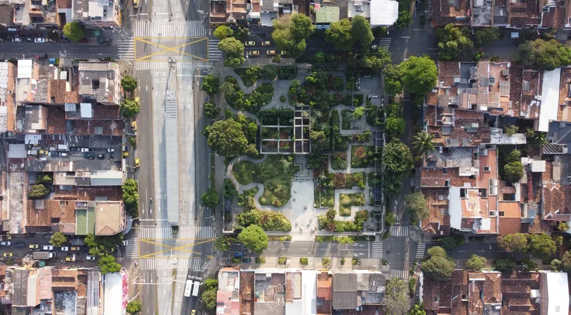 Drone view of terraced park inserted between dense urban blocks and a wide avenue