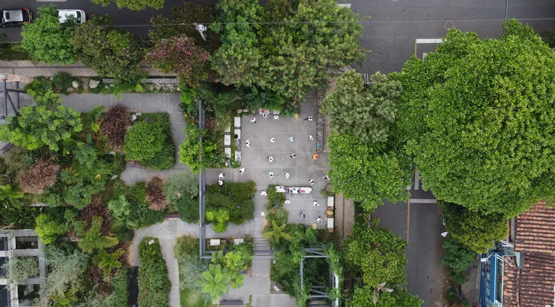 Overhead view of paved courtyard with white tables and chairs surrounded by mature trees and landscaping