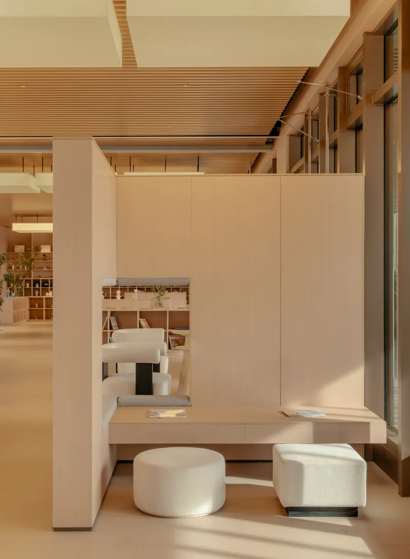 Workspace nook with pale wood desk and cylindrical fabric stools beneath the slatted ceiling