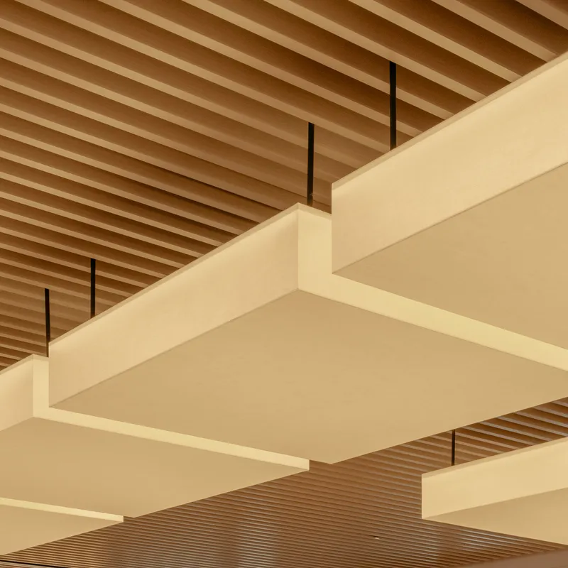 Detail view of layered pale panels suspended by black rods below the ribbed timber ceiling