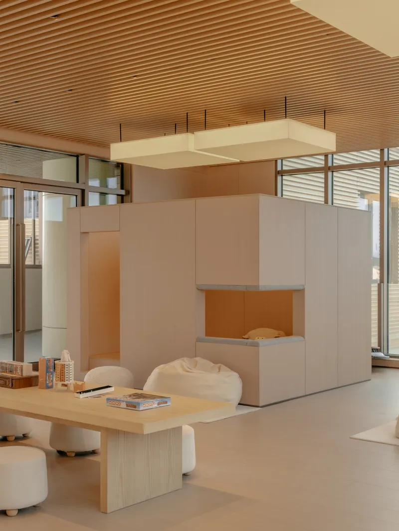 Reading nook with freestanding white cubicle, horizontal wood slat ceiling, and curved seating on polished floor