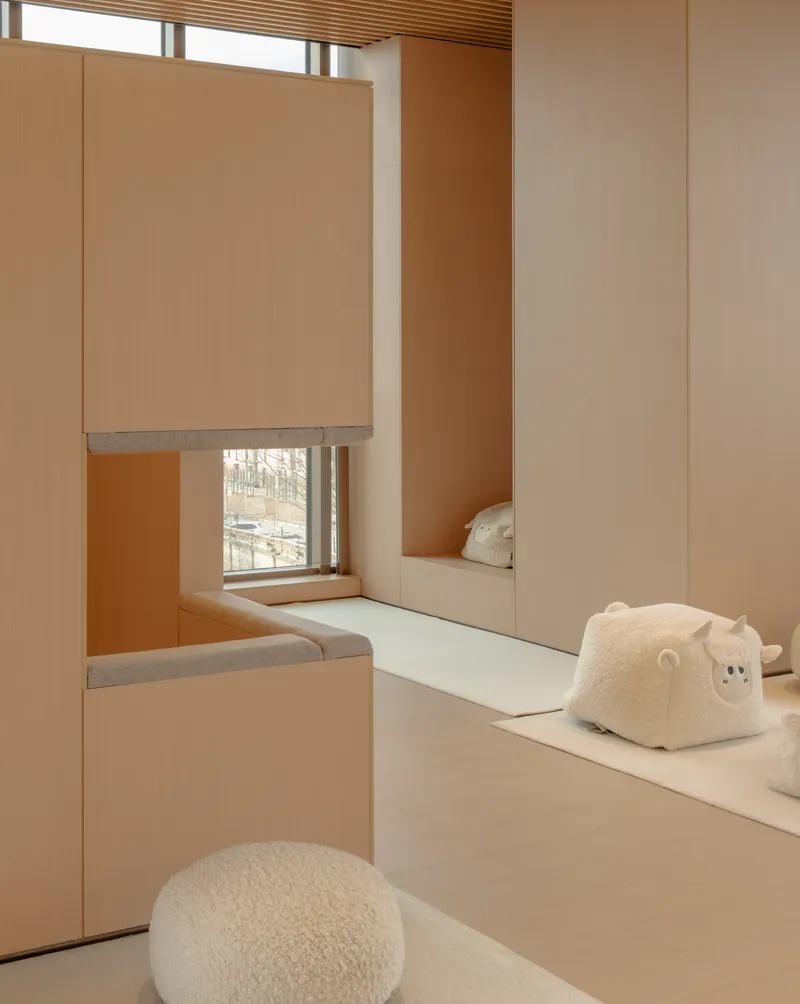 Mirrored alcove with window seat, roller shade, and sculptural white seating elements on pale flooring
