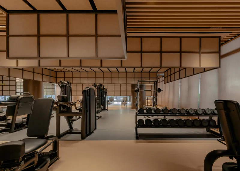 Fitness room with weight racks and exercise equipment beneath translucent panel walls and ceiling grid