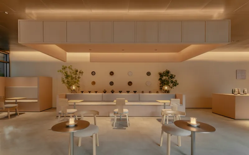 Reception counter with circular ceiling coffers, wall-mounted ceramic vessels and scattered low tables lit by candles