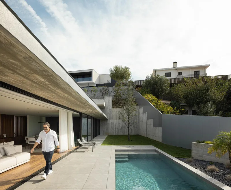 Covered terrace opening to a swimming pool and grassed courtyard enclosed by board-formed concrete walls