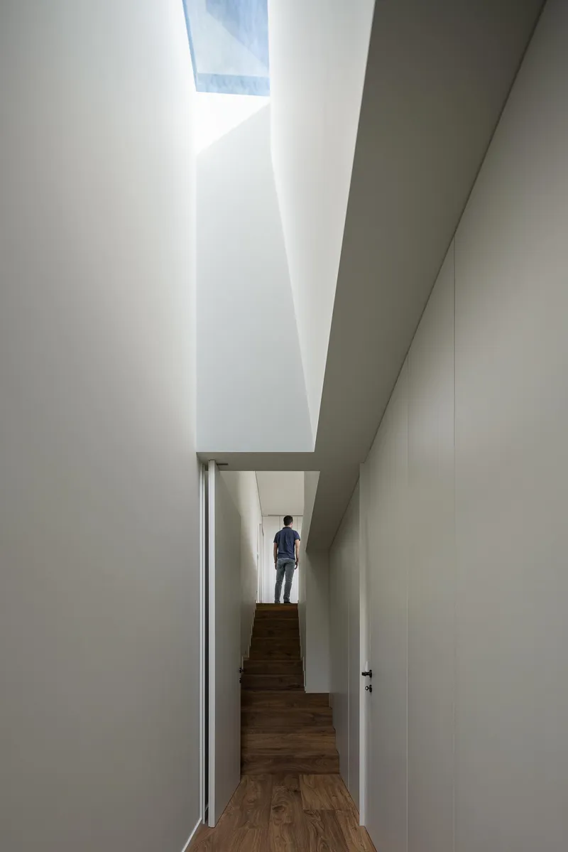 Corridor with a skylight above timber stairs and a figure standing in the landing beyond