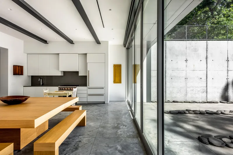 Kitchen with white cabinetry and sliding glass doors opening to a pebbled courtyard with concrete wall