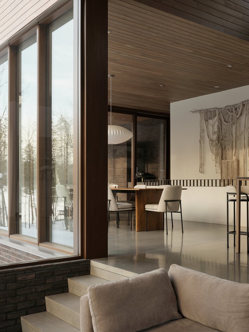 Split-level interior with dining area beyond glazed doors and timber soffit extending from exterior to interior