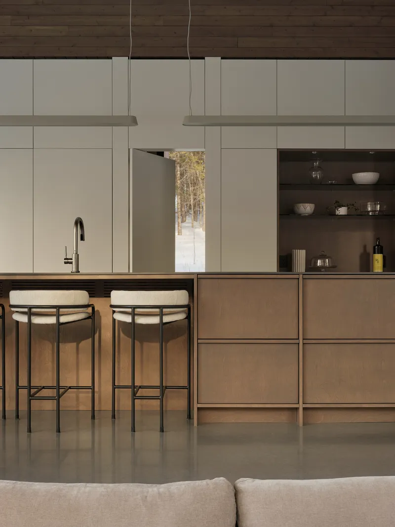 Kitchen island with integrated sink and two bar stools facing white millwork and shelving