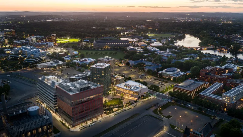 Aerial view of campus buildings and river at twilight with illuminated fields