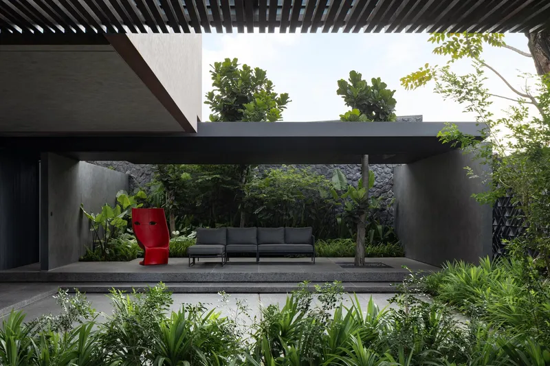 Covered terrace with timber pergola sheltering seating area flanked by planted beds and mature trees