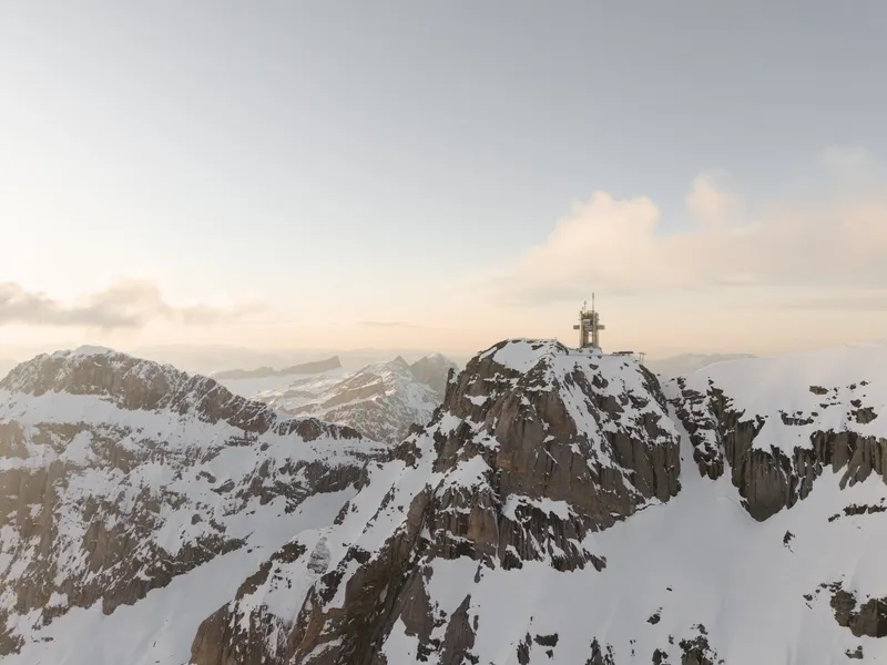 Observation structure with white mast perched atop a rocky summit at sunrise