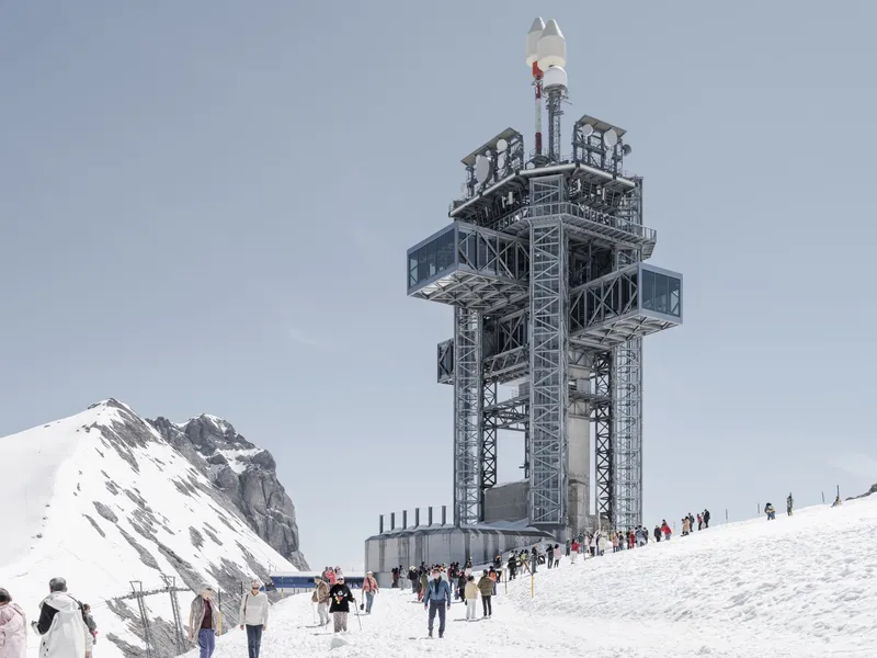 Lattice steel tower with cantilevered platforms and visitors gathered on the snow-covered plaza below