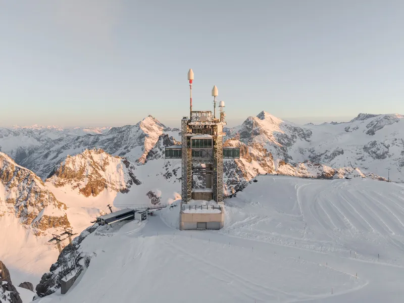Aerial view of the vertical observation tower on a snow-covered mountain ridge at sunrise