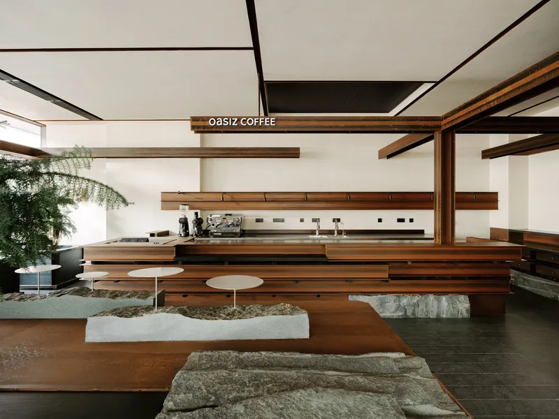 Coffee bar with tiered timber seating platforms and rough stone bases surrounding low white tables