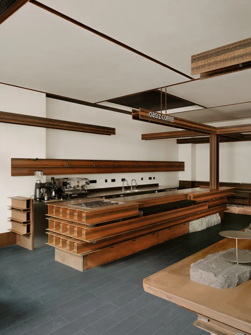 Coffee bar with stacked timber counter and stone-topped seating under exposed wood beams