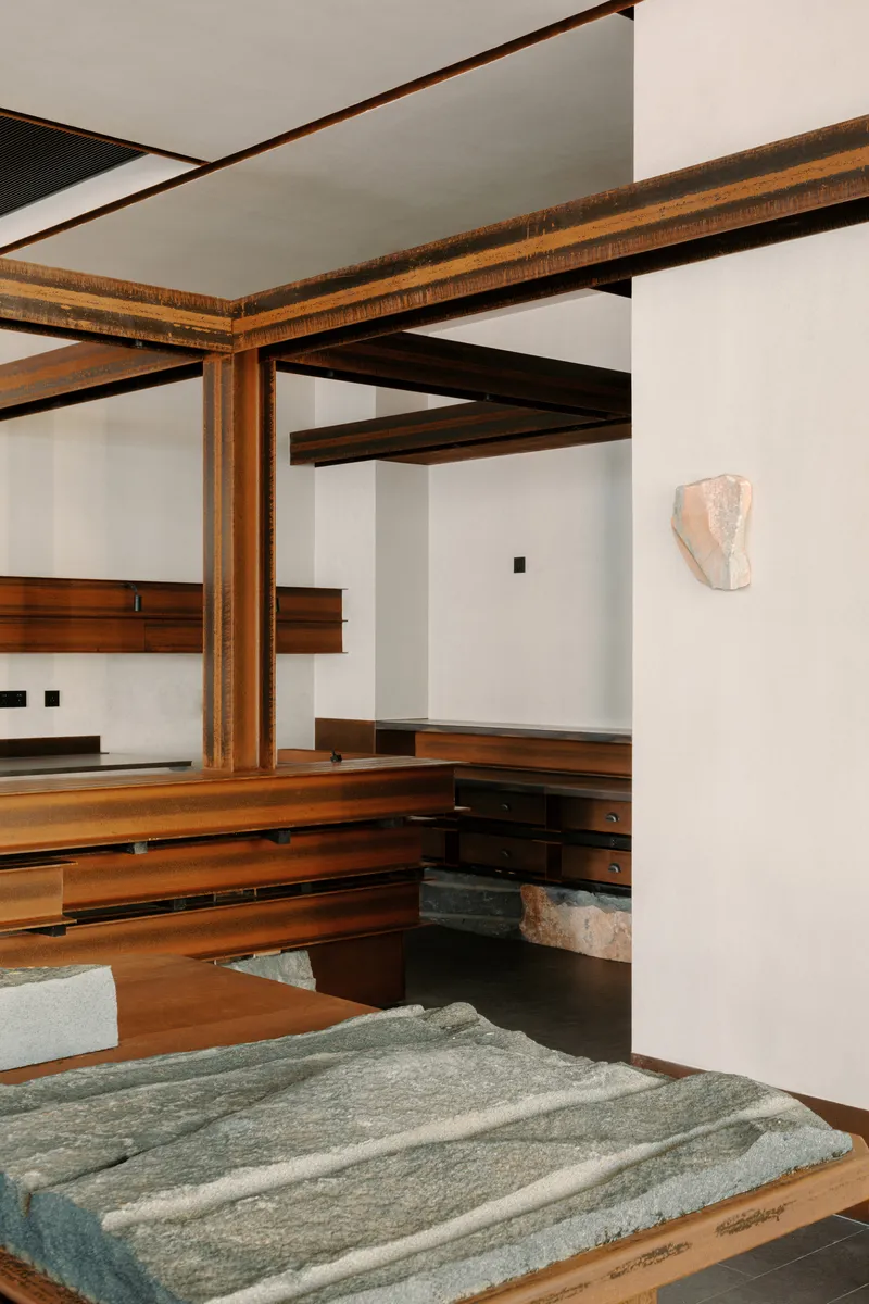 Interior corner showing laminated timber columns and carved stone panel on low table
