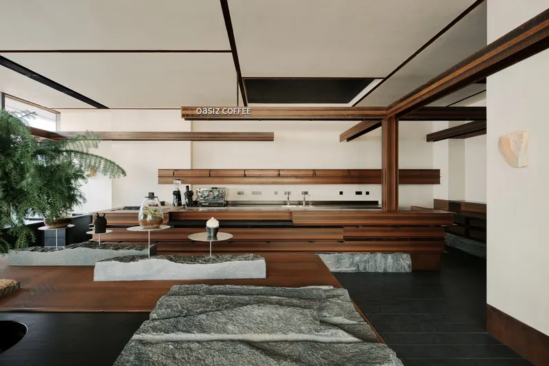 Interior view of coffee bar with exposed timber beams, stone-topped seating platforms and potted palm tree