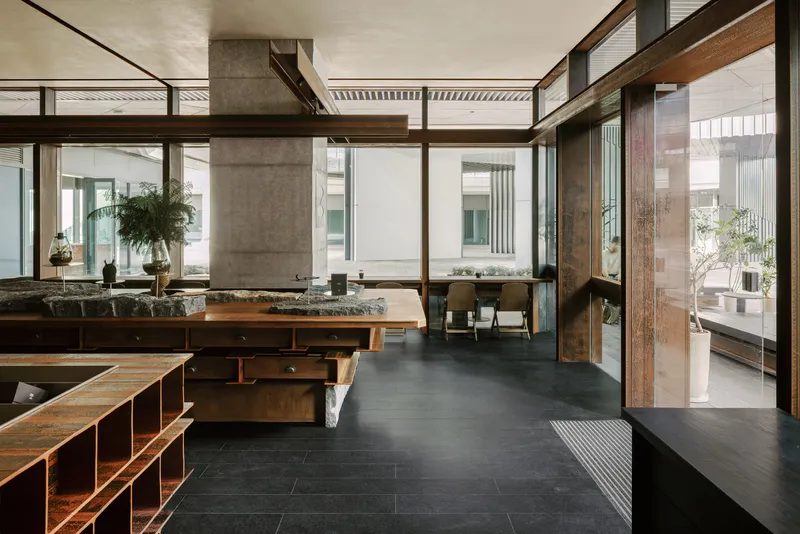 Interior looking through timber-framed glazing toward courtyard with concrete column and dining area beyond