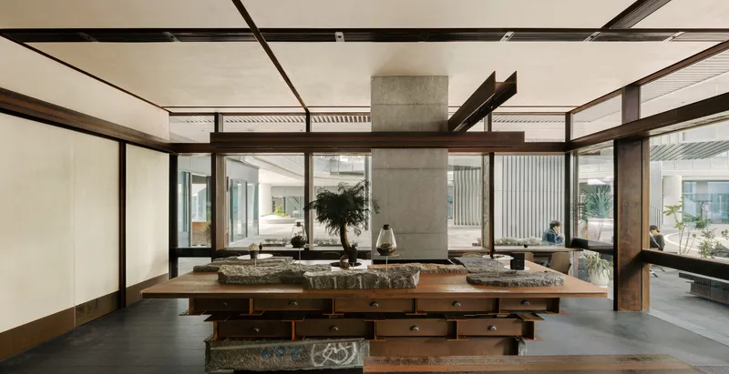 Wide view of the communal table with stone surfaces surrounded by glazed walls opening to courtyard