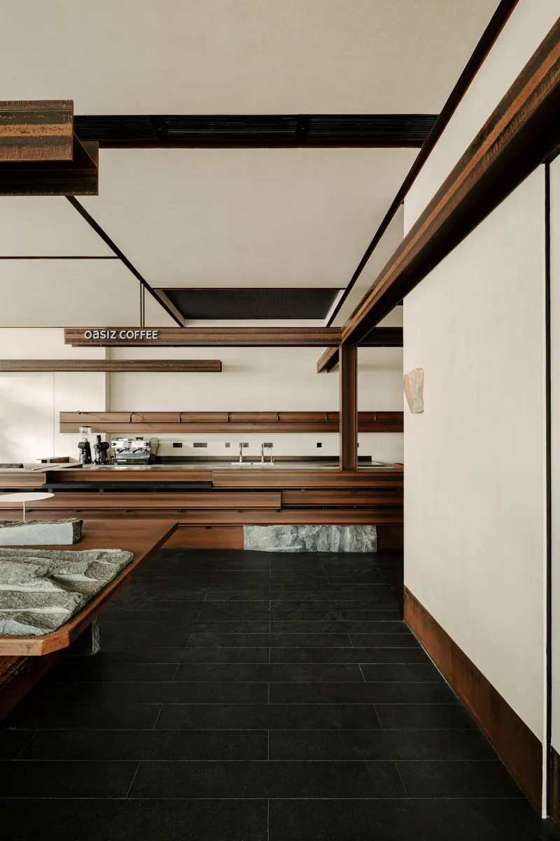 Coffee service counter with horizontal timber shelving and exposed beam ceiling above dark floor tiles