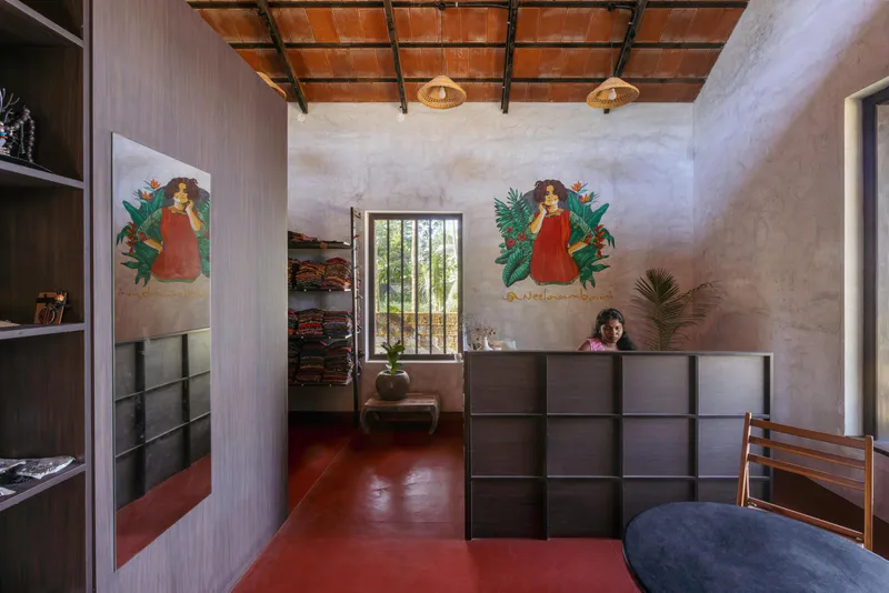 Interior room with red oxide floor, timber grid ceiling and twin murals above a grey metal partition