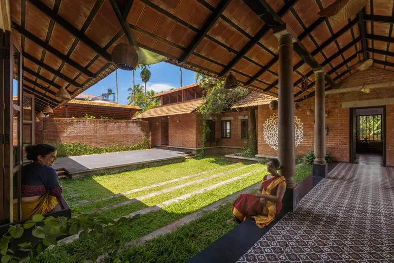 Interior courtyard with grass lawn striped with concrete bands viewed from a tiled verandah corridor