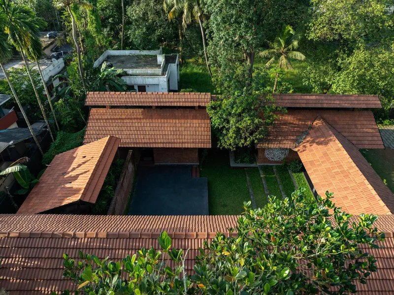 Drone view showing staggered clay tile rooflines around a courtyard with pool and palm trees
