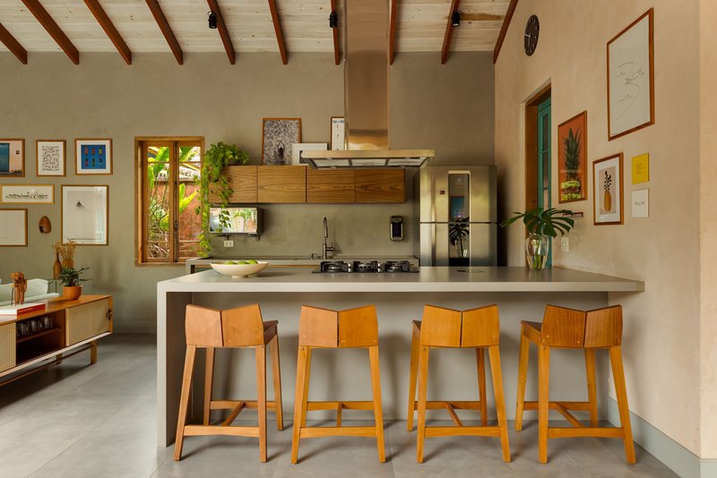 Kitchen island with four wooden bar stools beneath exposed timber rafters and polished concrete floor