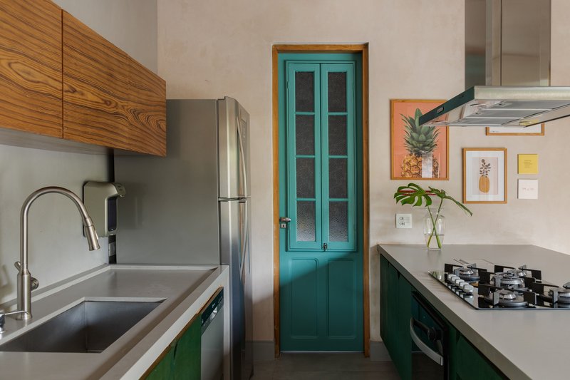 Turquoise paneled door with glazed upper section set between wooden cabinetry and green lower units