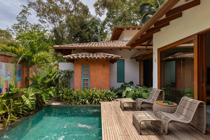 Timber deck surrounding small pool with lounge chairs facing ochre and white stucco walls