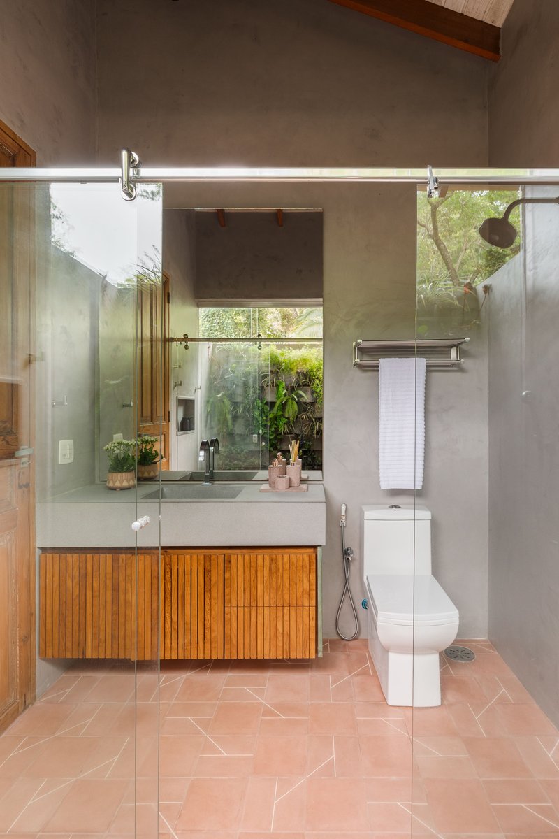 Bathroom vanity with slatted timber cabinet and sliding glass partition beneath exposed timber ceiling