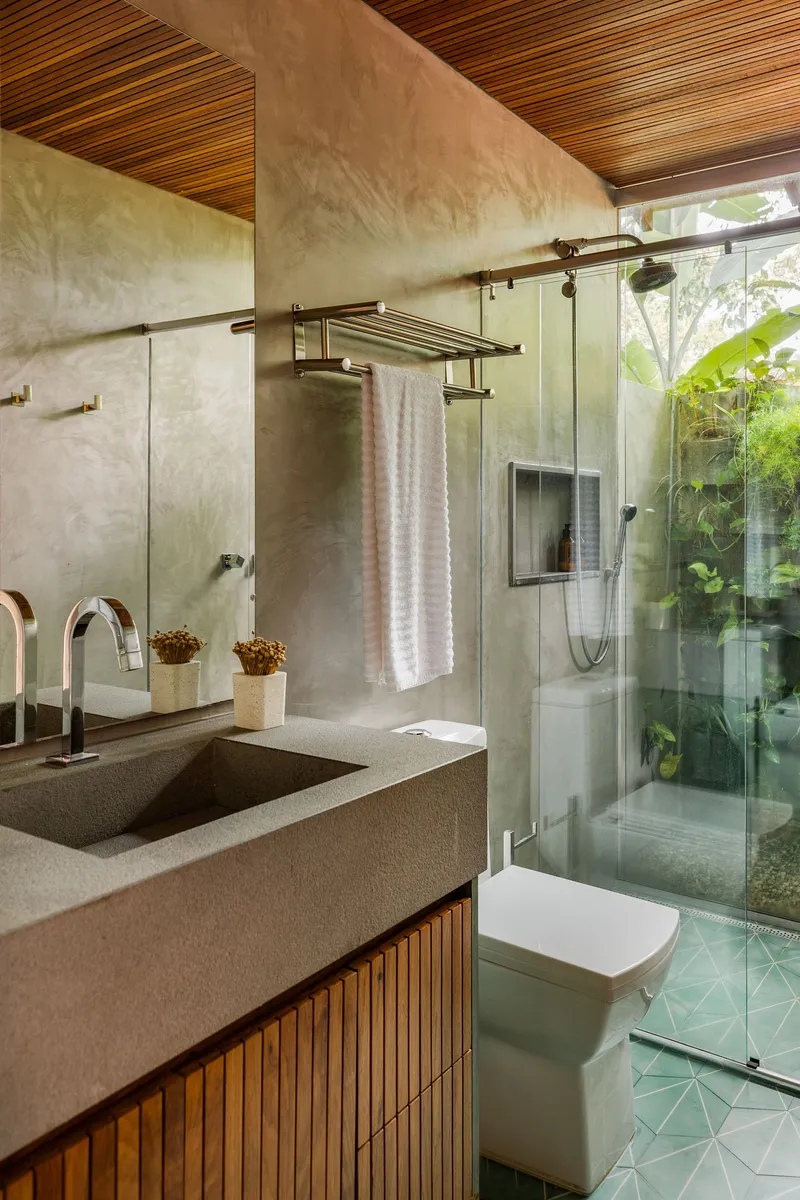 Bathroom with timber slat ceiling, terrazzo vanity and glass shower enclosure overlooking green courtyard