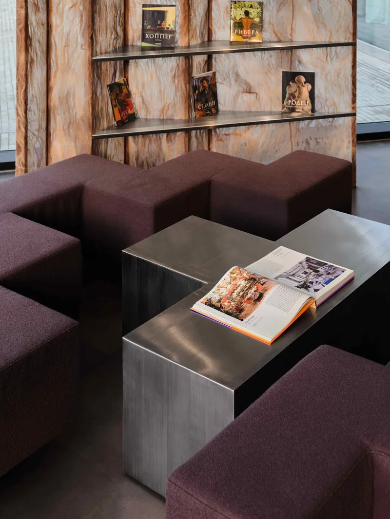 Close-up of metal cube side tables with burgundy upholstered seating against a veined copper wall panel