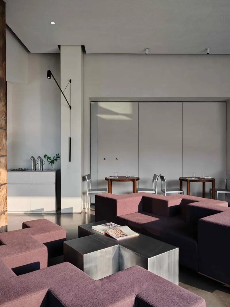 Lounge area with modular burgundy seating facing a white dining niche with recessed lighting from above