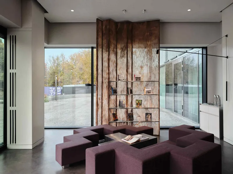 Interior lounge with purple modular seating facing a central wood-clad shelving wall flanked by full-height glazing
