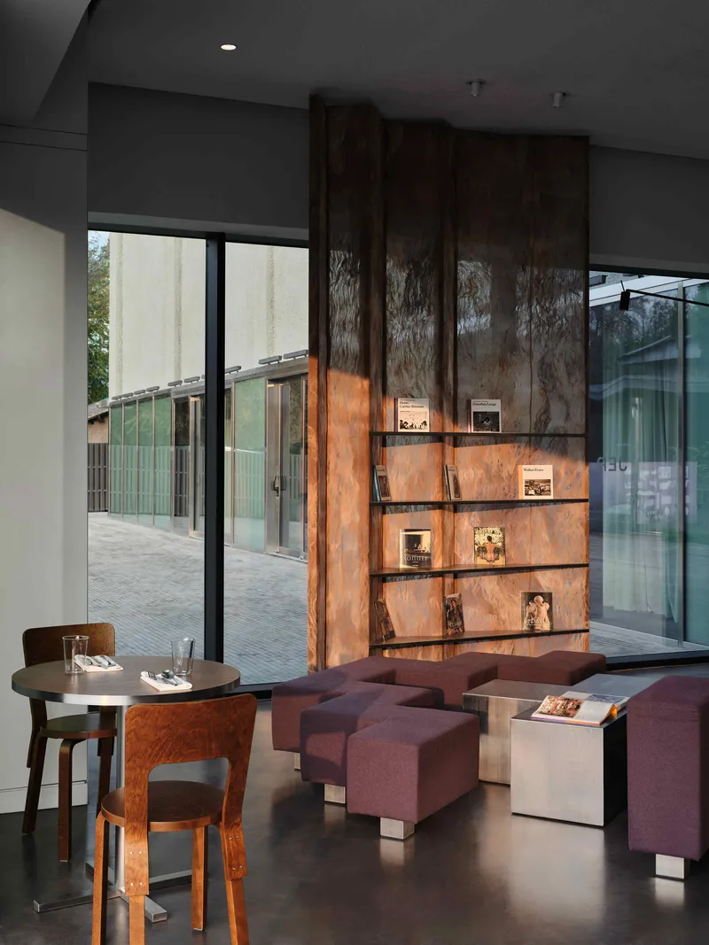 Backlit wood veneer display shelves with cutout animal silhouettes, overlooking a paved courtyard through glass doors