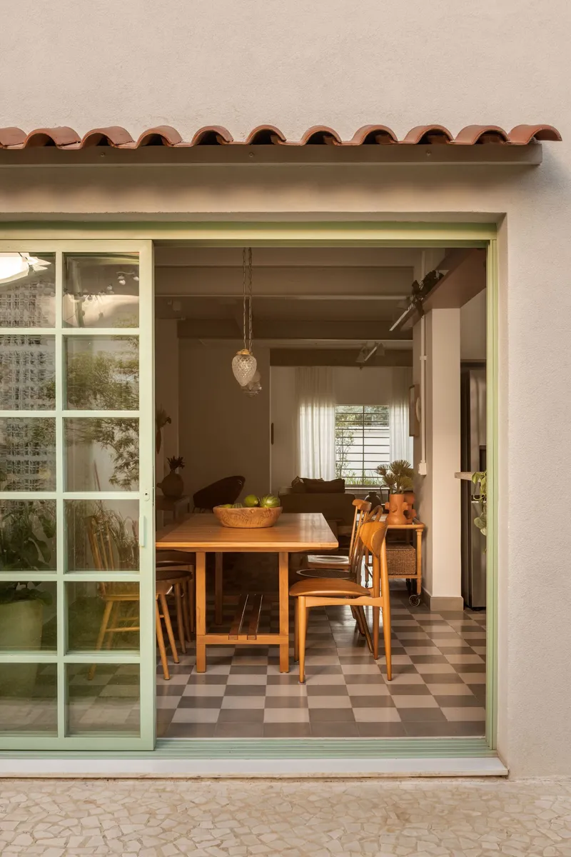 View through pale green sliding door to dining room with terracotta tile awning detail above