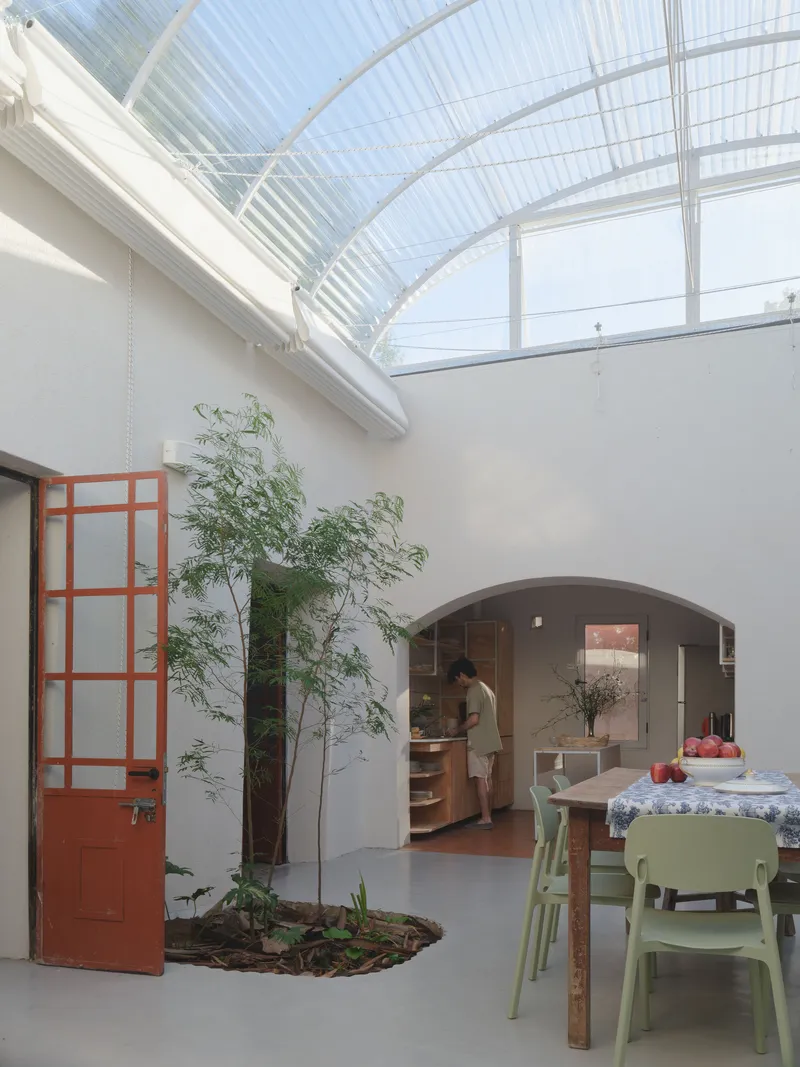 View through terracotta glazed door toward kitchen opening beneath the translucent barrel vault ceiling