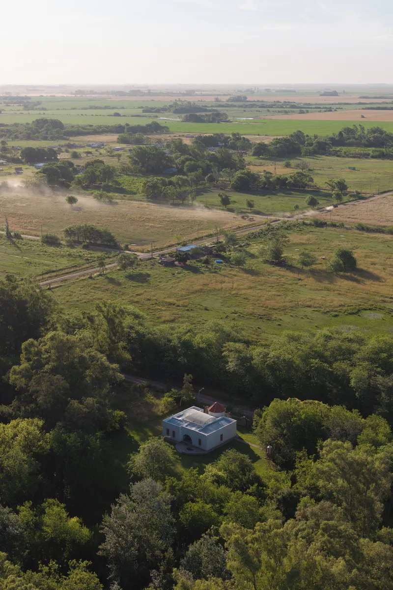 Aerial view of the white structure surrounded by dense tree canopy in agricultural landscape