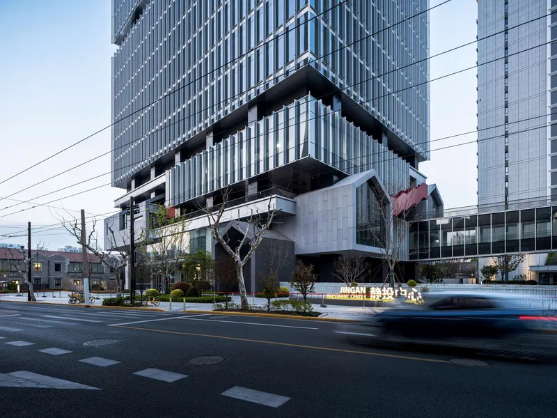 Street view of the vertically ribbed facade with cantilevered volumes above a landscaped plaza at dusk