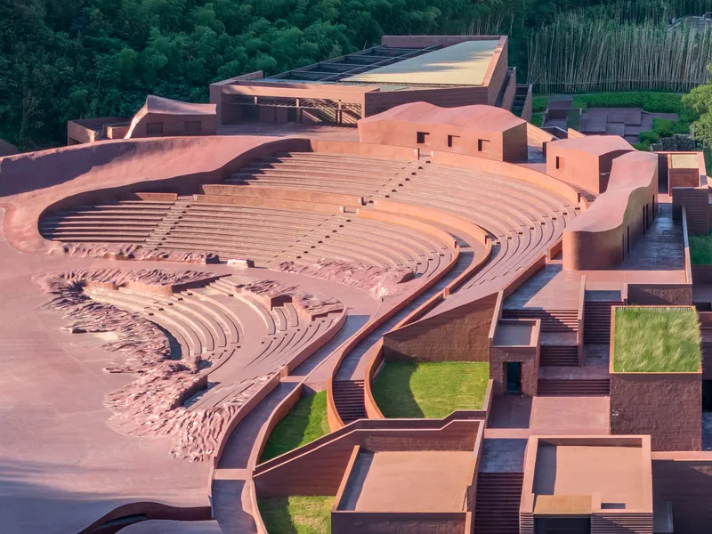 Aerial view of the tiered amphitheatre carved into red earth with lawn courtyards below