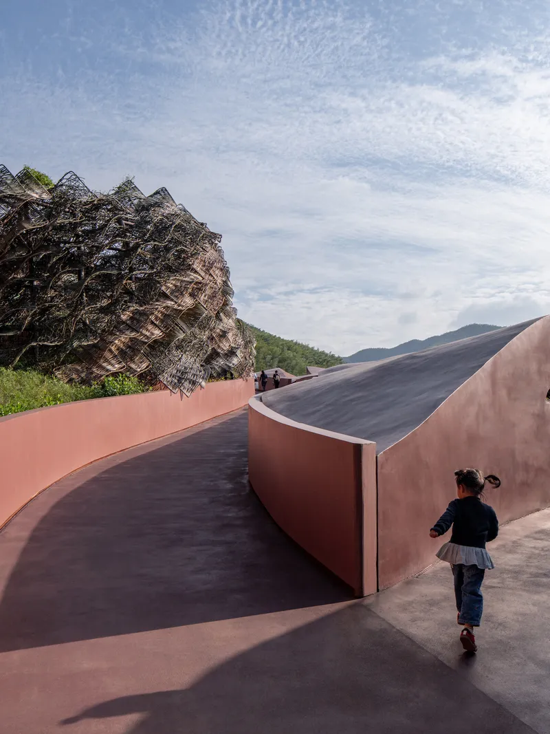 Curving ramp with weathered steel walls as a child runs along the sloped pathway