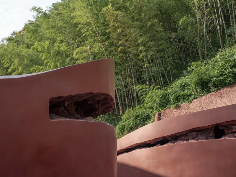 Close-up of corten steel roof planes with organic apertures framed by bamboo grove