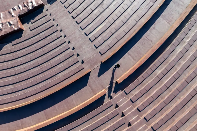 Aerial view of timber-clad terraced seating with a single figure casting long shadows