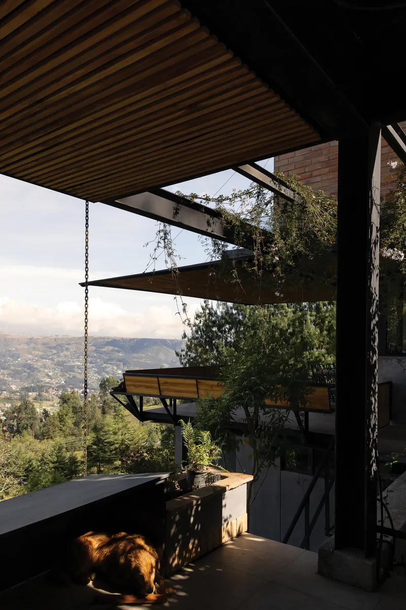 Covered terrace with timber slat ceiling and chain-suspended bench overlooking the valley