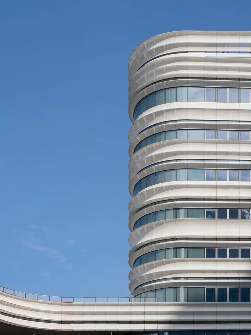 Close-up of the cylindrical tower with horizontal white banding against a clear blue sky